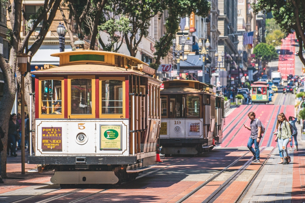 two tram cars passing on the sunny and bustling streets of San Francisco