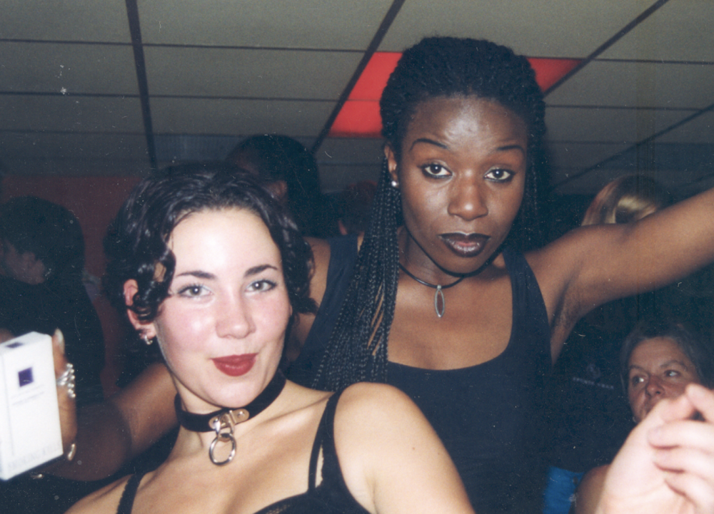A person with mid length dark hair and white skin and a person with dark brown skin and long dark braids stood next to them