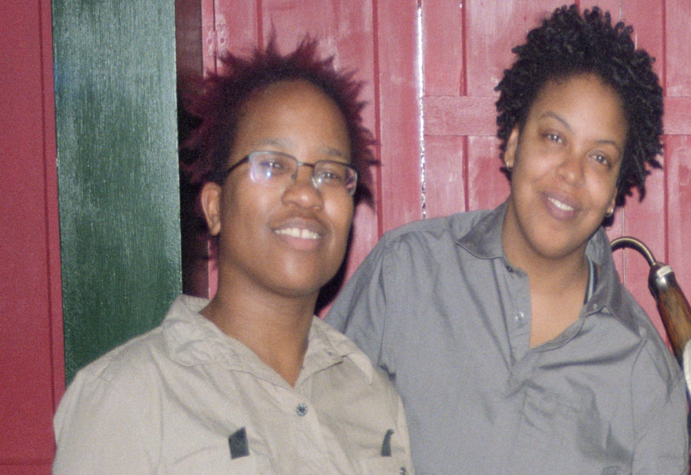 Two black women with short hair, Claud Cunningham and Paula Gannon-Lewis sit together