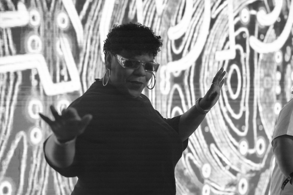 Mix-stress with short curly black hair and sunglasses performing at the MancUnity stage at Manchester Pride Festival in 2022