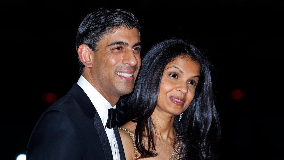 Rishi Sunak and his wife Akshata Murthy both has brown skin and black hair, they look happy and seem to be at a social event